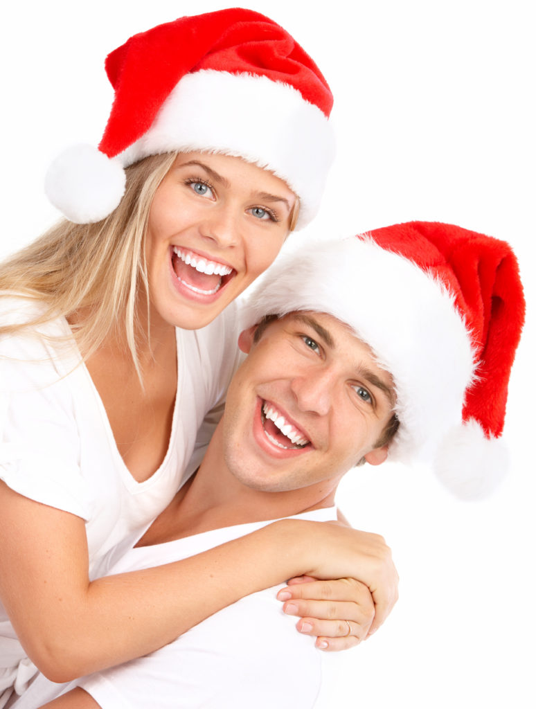 Young happy couple in Christmas hats. Isolated over white background